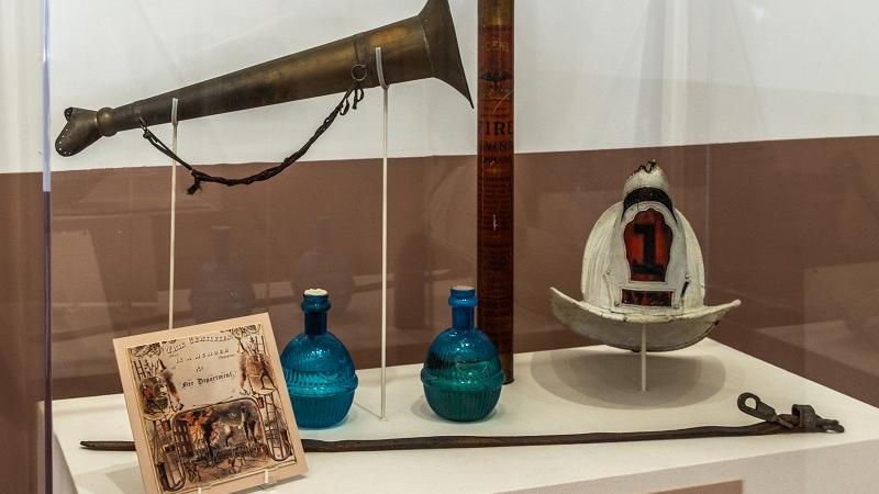 Exhibit case at Friendship Firehouse with horn and hat