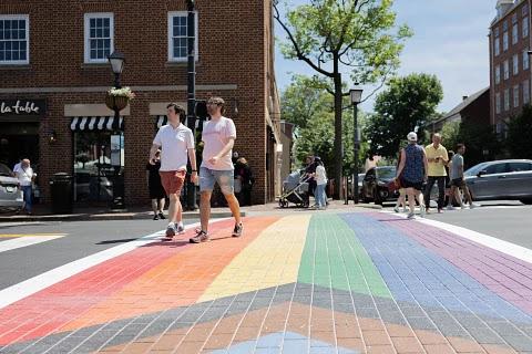 two people walking on rainbow crosswalk