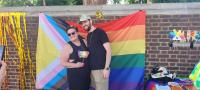 People posing in front of pride flag