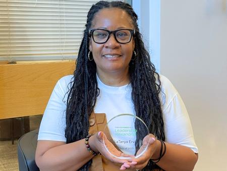 professional employee smiling and holding lucite presentation piece that says Leadership Alexandria
