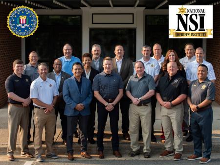 two rows of 18 law enforcement executives wearing business casual pants and agency golf-style shirts