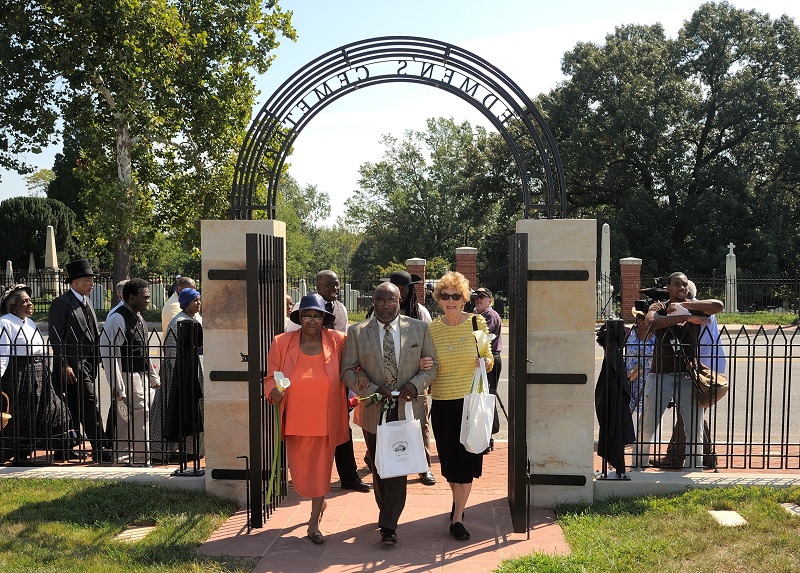 Participants at the 5th anniversary walk through the gates into the cemetery