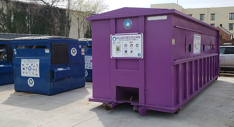 Photo of a large purple glass recycling bin at one of Alexandria's recycling drop-off centers