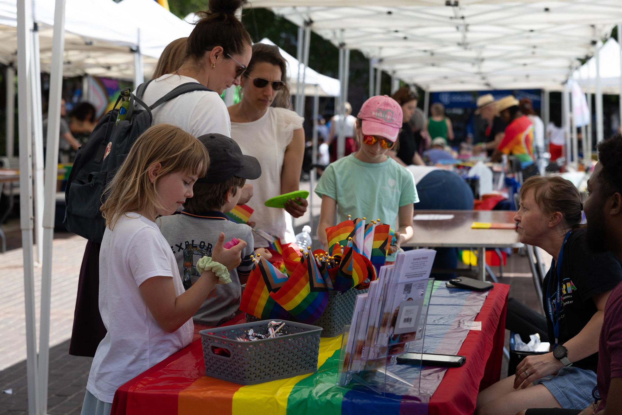 Participants at Pride Fair gathered around table with rainbow tablecloth