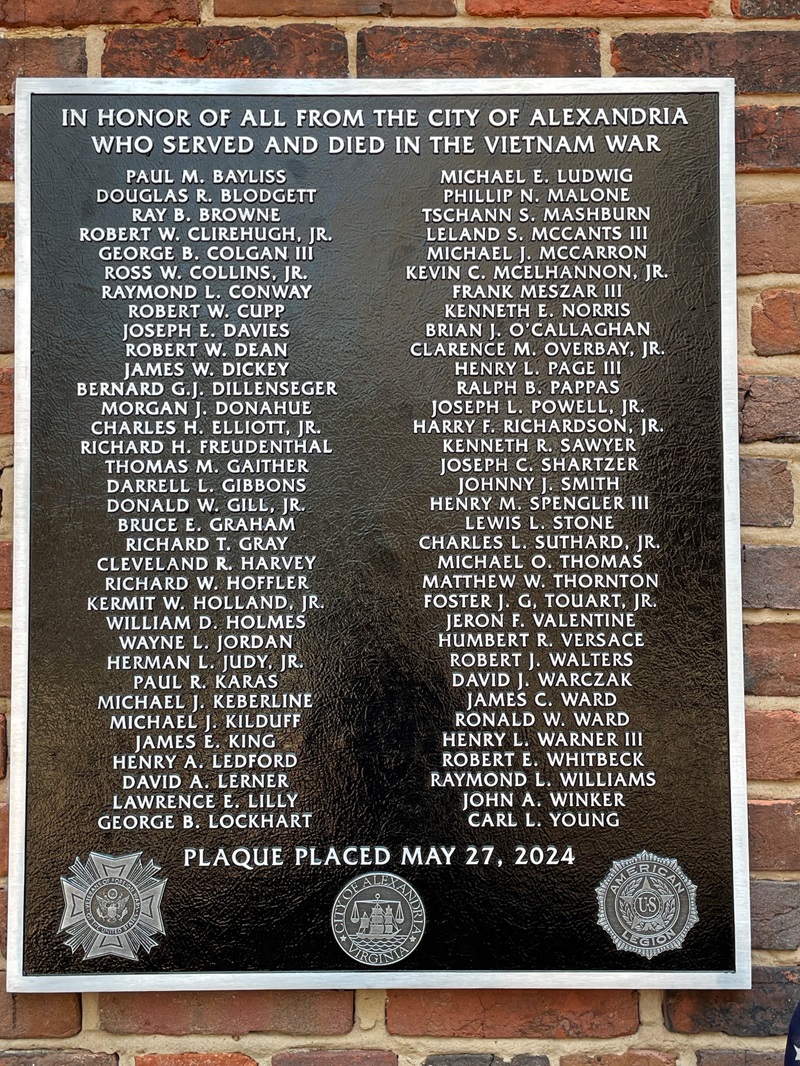 Bronze plaque listing names, installed on brick wall