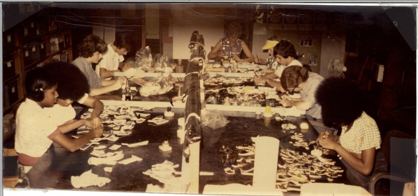 Eight volunteers work together at long tables in the lab to mend artifacts together to form more complete vessels