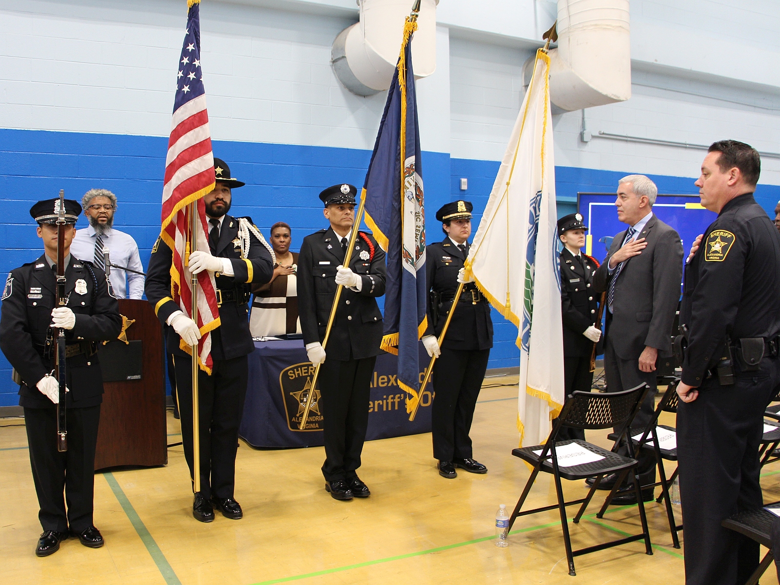 Public safety personnel in formal uniforms at a ceremony where the honor guard is holding flags