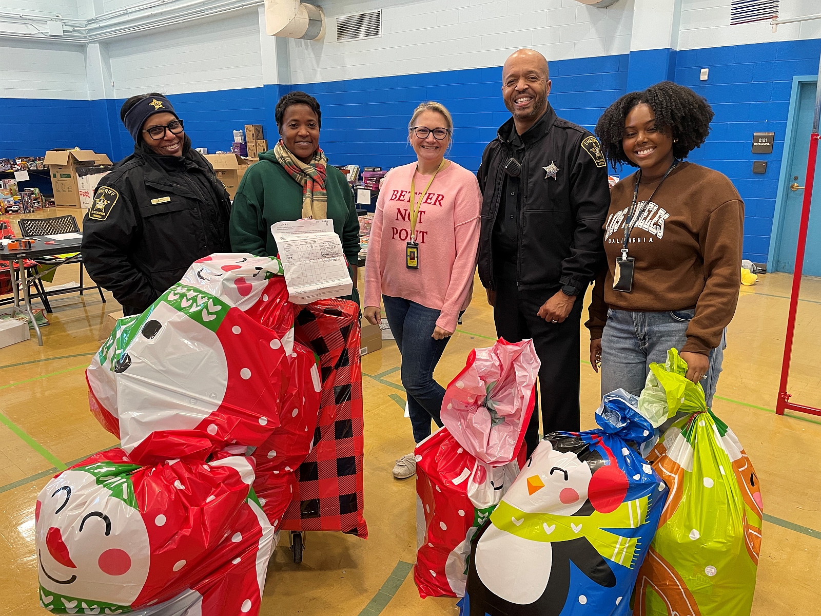 Two deputies and three civilians with bags of Christmas gifts around them