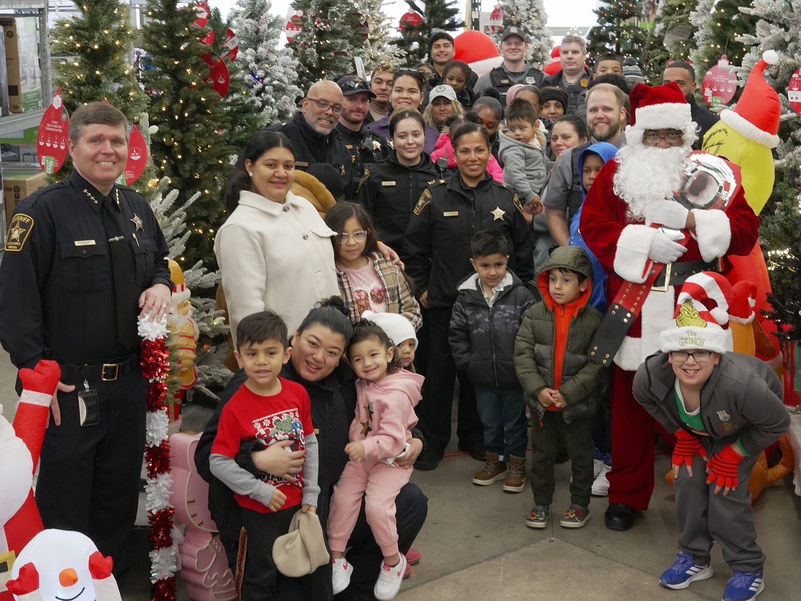 Sheriff, deputies and police officers with small children and Santa in a story with lots of holiday decorations