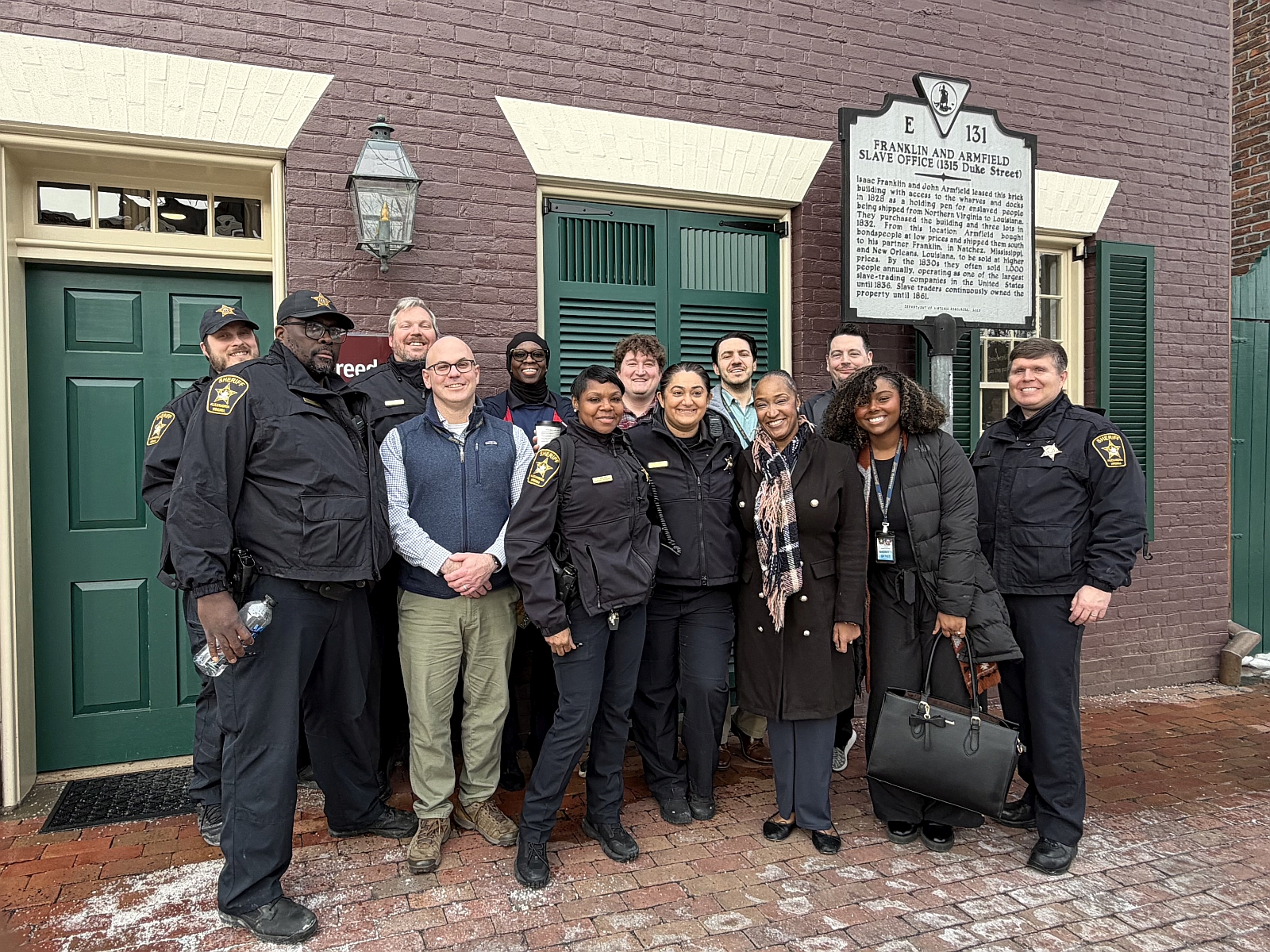 Deputies in uniform and professional staff standing in front of the Freedom House museum with a historic marker in the background