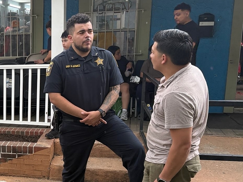 Deputy in blue uniform speaking with local business owner outside a hair salon