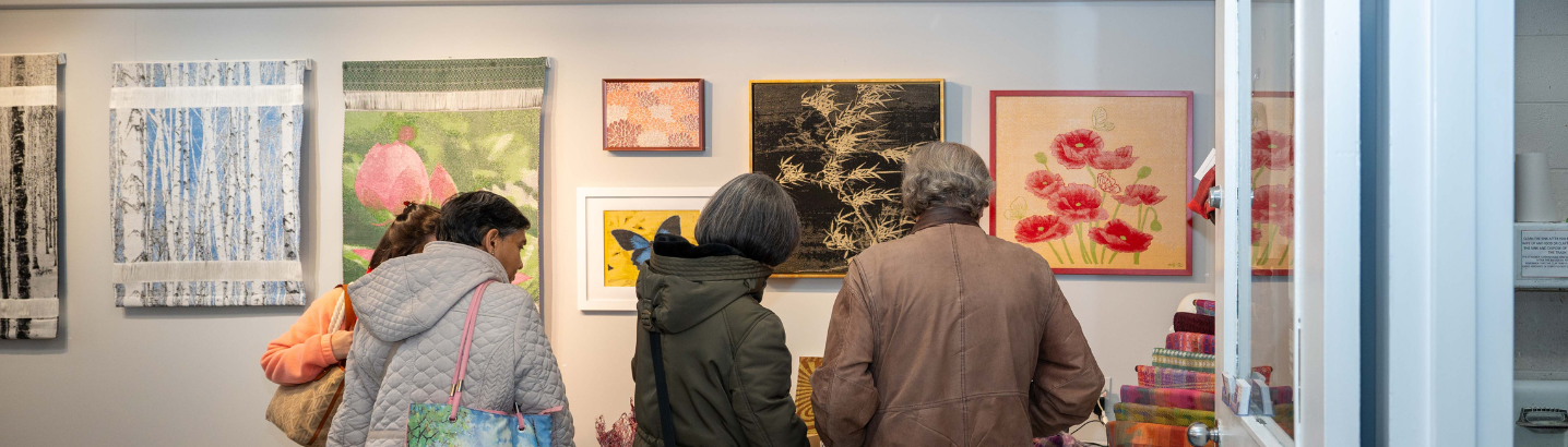 A group of three people look at art at a gallery