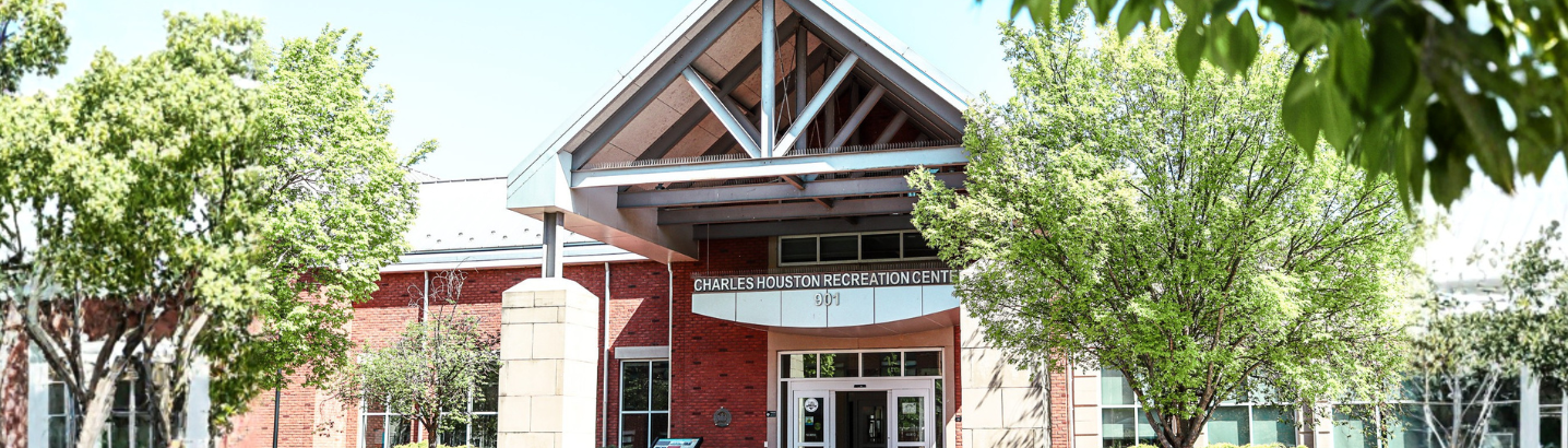 View of the front of the Charles Houston recreation center facility from the street with trees on either side