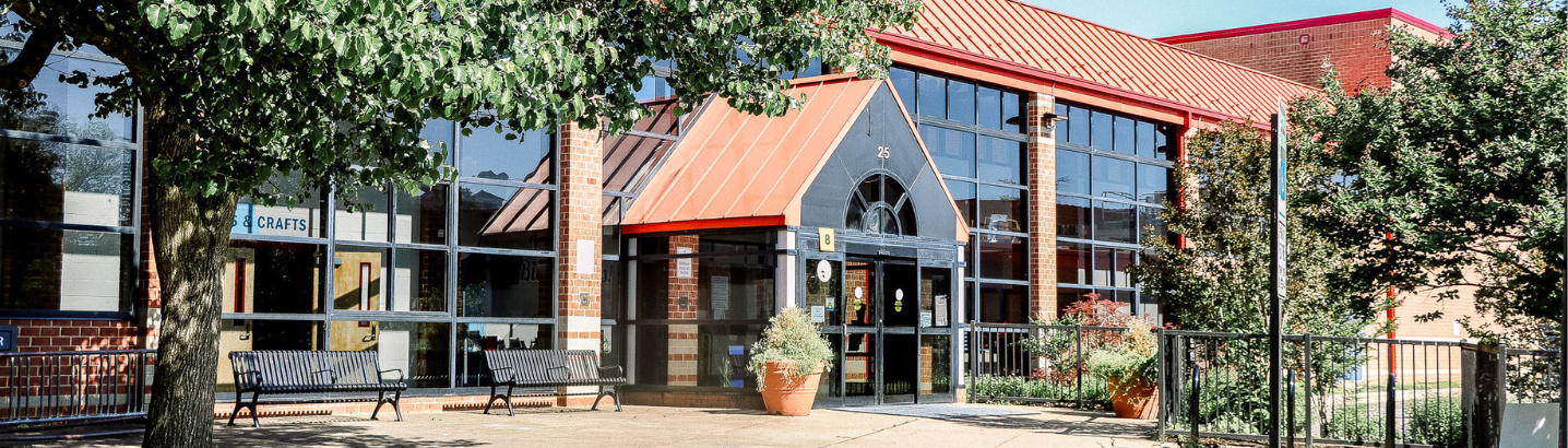 Front of the Leonard Armstrong rec center with trees on either side of the frame of the picture