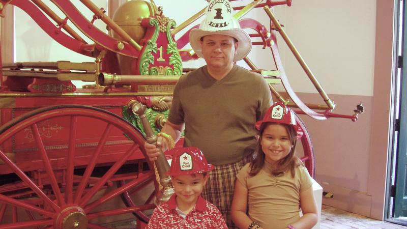 Friendship Firehouse Father's Day Open House. Family wearing fire hats, with the Suction Pumper (2004)