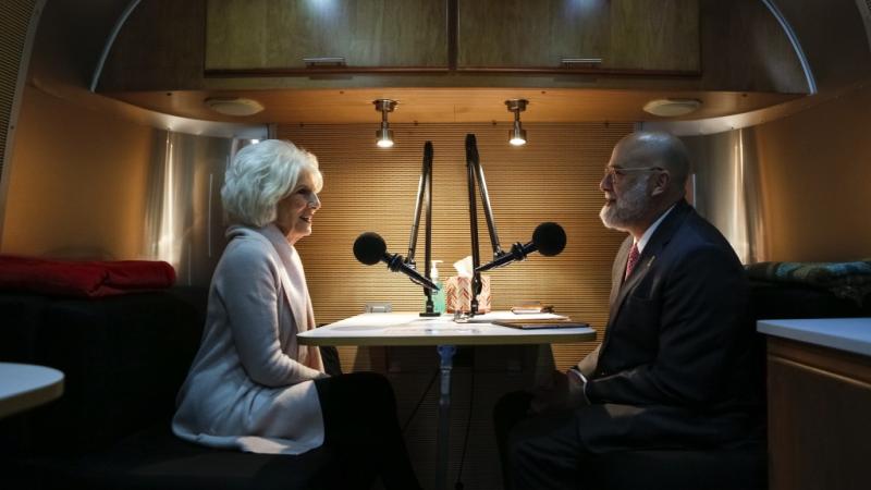 Two people speaking into recording microphones