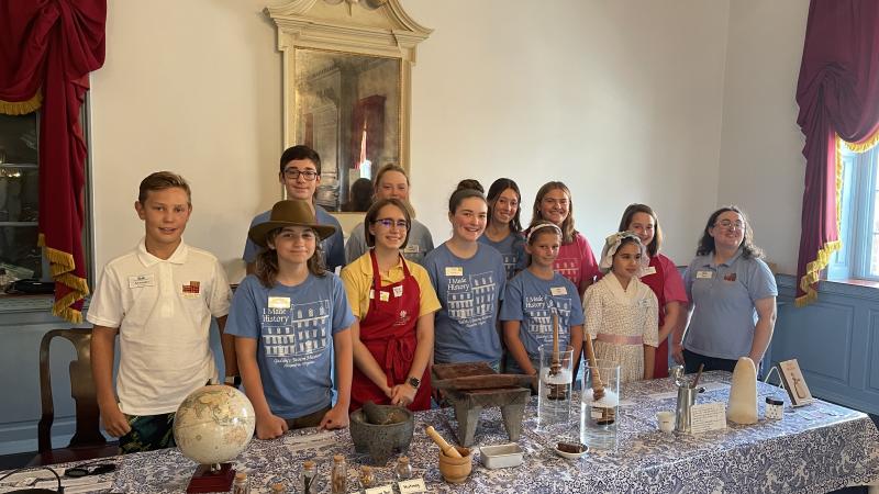 Group of teenagers standing behind a table with chocolate making supplies in ballroom