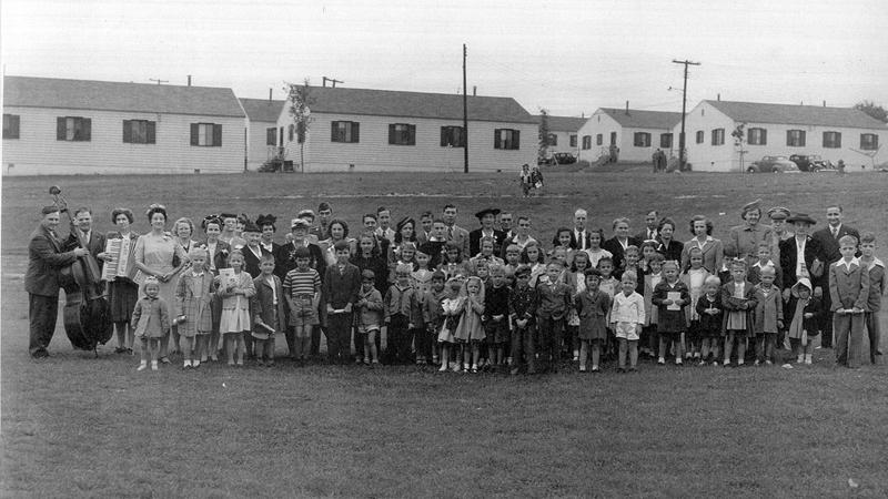 A group of people lined up for the photograph, in front of Chinquapin Village housing