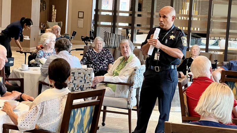 Deputy standing and speaking to several seniors seated a small tables