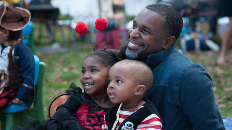 Family of three smiling, kids in Halloween costumes