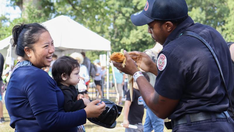 Firefighter showing a bearded dragon to a parent and child