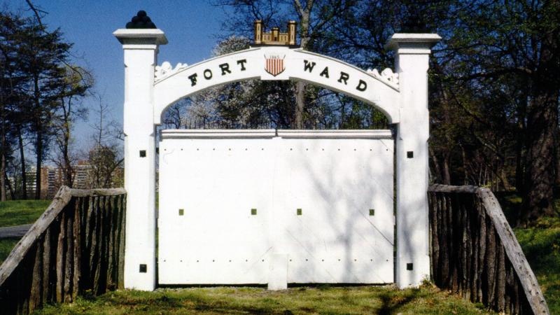 White, two door gate, with arch on top that says Fort Ward