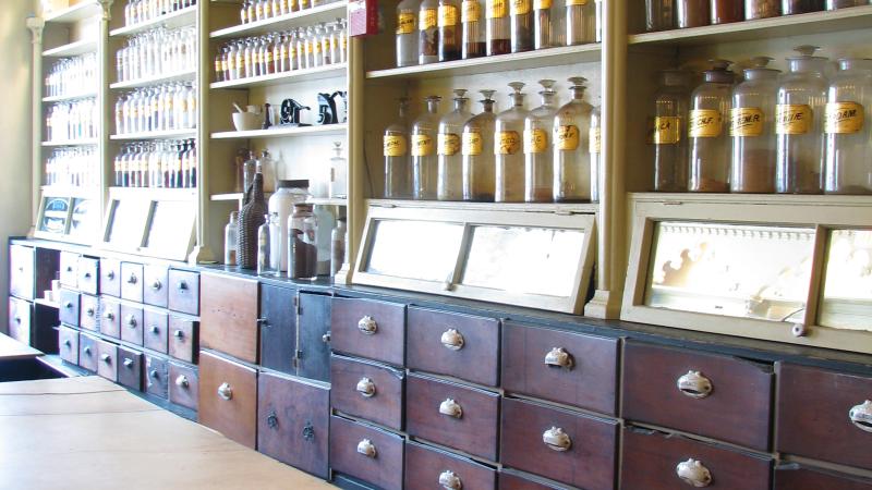 Shelves with bottles and drawers underneath. Counter holding bowl and spoon