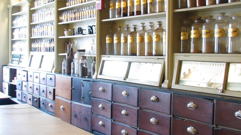 Shelves with bottles and drawers underneath. Counter holding bowl and spoon