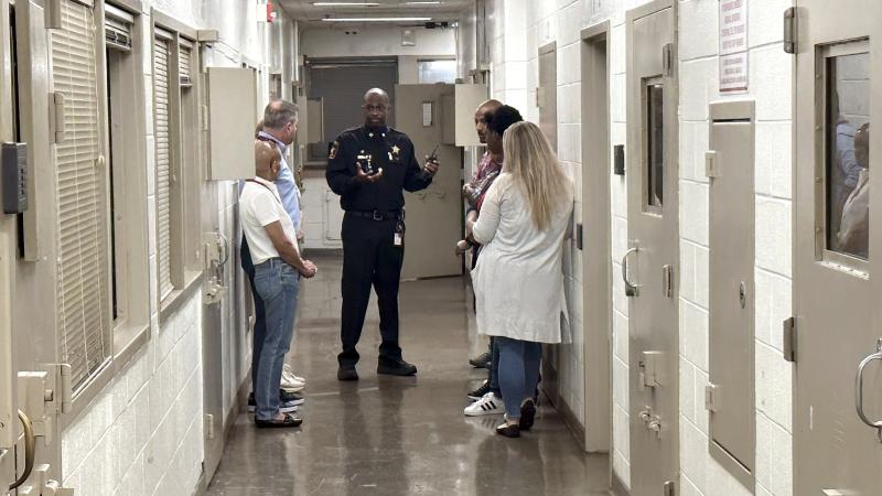 Sheriff's Office commander in blue uniform giving tour to several community members inside the jail