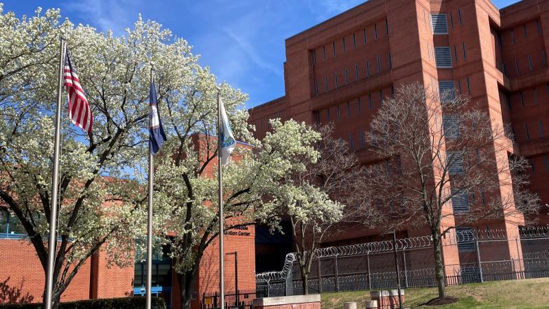 detention center with orangish brick and blue windows and three flagpoles outside
