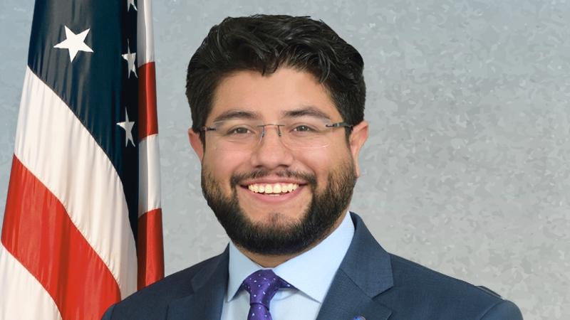 Photo of Councilman Aguirre on a blue background with the American Flag