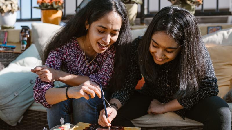 A mother and older daughter smiling while painting