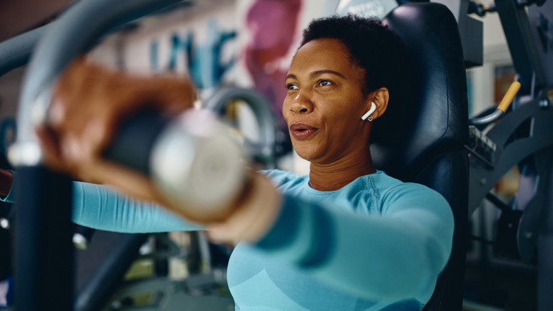 Image of a woman dressed in blue working out on a shoulder press machine
