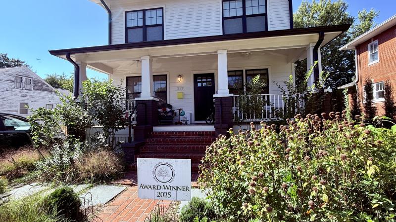 Image of a white house with black trims and a brick path with a very green front yard