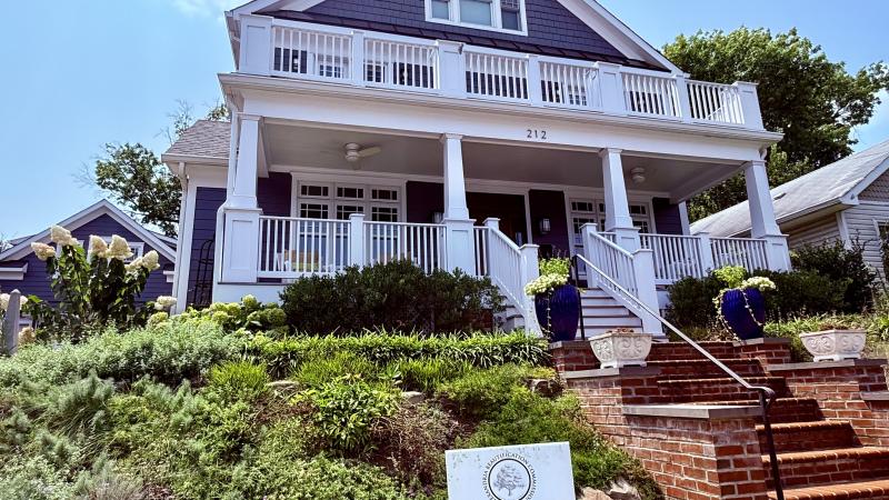 A sign that says Award Winner 2025 stuck in the ground in front of a blue and white house with a nice front yard and lots of steps