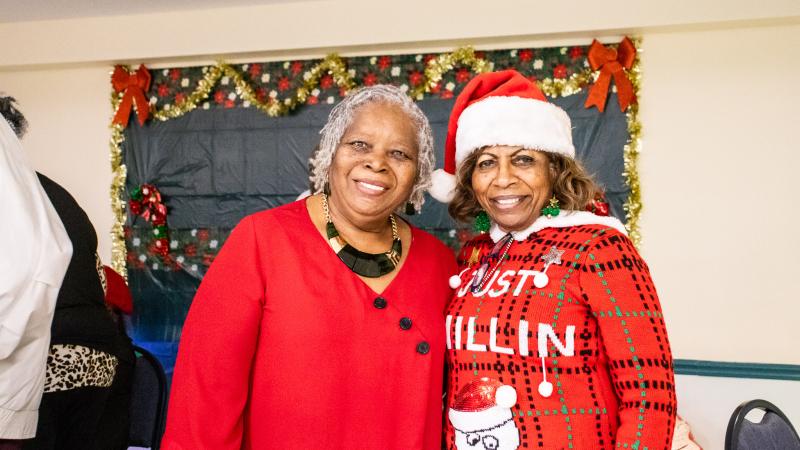 Two females dressed in festive outfits smiling for the camera