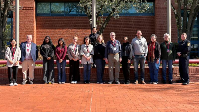 Several civilians standing in a line with the Sheriff to the right and a deputy alone in the second row.