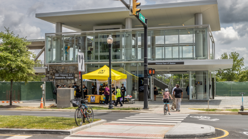 front of Potomac Yard metro station with a WMATA tent and people in front of the building