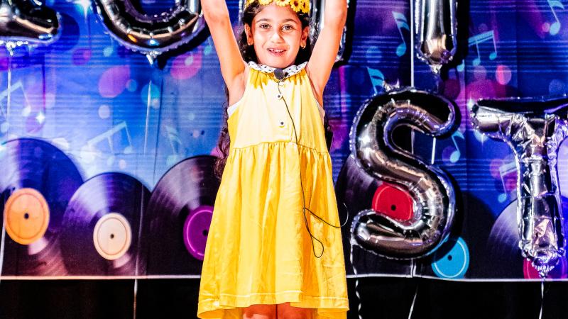 Performer in yellow with her two hands up