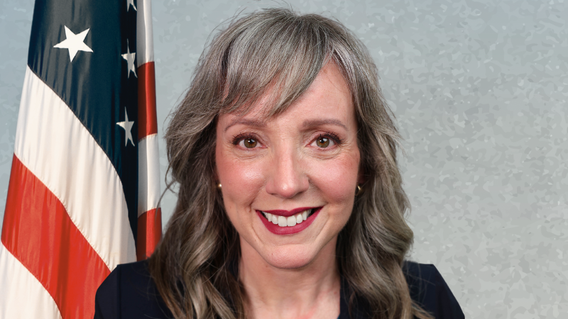 woman with flag in background smiling at camera