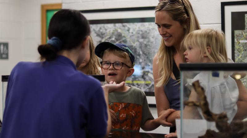 Family interacting with a live animal with the help of a Nature Center staff member