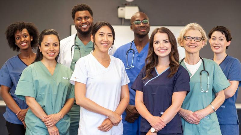 A group of people with nursing scrubs on posing for a picture. 