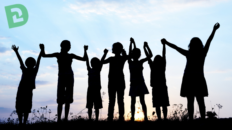 Silhouette of children holding hands with the sunrise in the background
