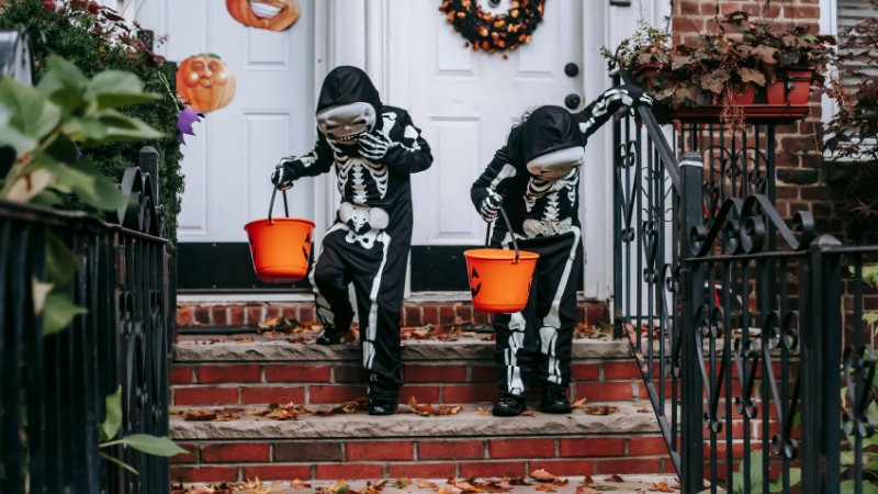 two kids stand on steps with halloween buckets in costumes