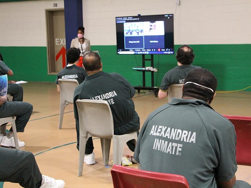 inmates watching a video screen with presenters