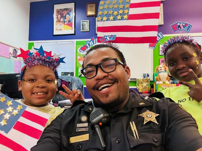 deputy with two children wearing Independence Day decorations and holding handmade U.S. flag