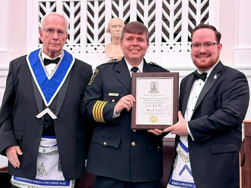 Two men in wearing Masonic regalia presenting an award plaque to Sheriff standing in the middle.