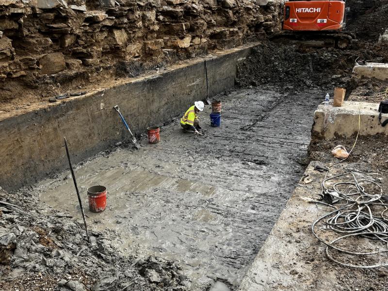 Archaeologist in canal lock, orange safety fencing