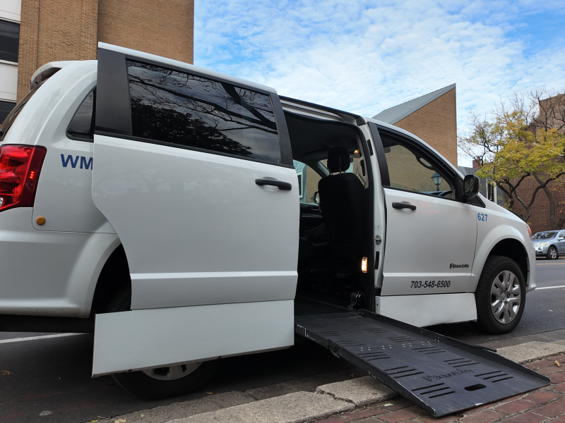 A paratransit van with the door open and the ramp down.