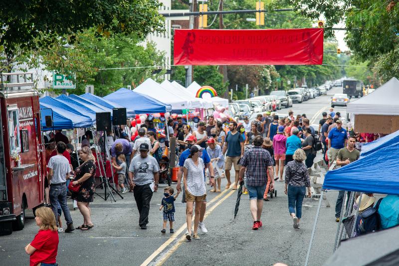 Adults and children walk on between vendor tents at the Friendship Firehouse Festival.